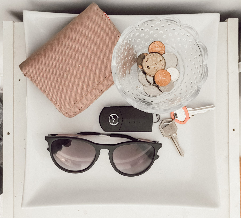 Wallet, keys, sunglasses, and change on a tray
