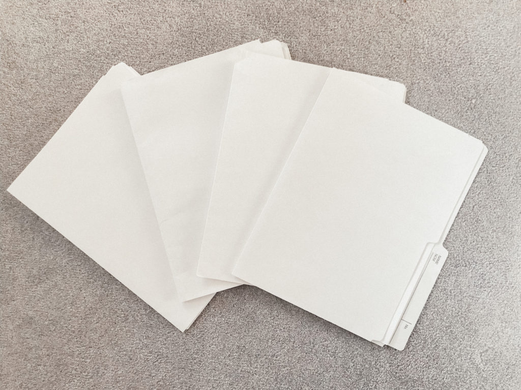 Four white file folders on a grey carpet
